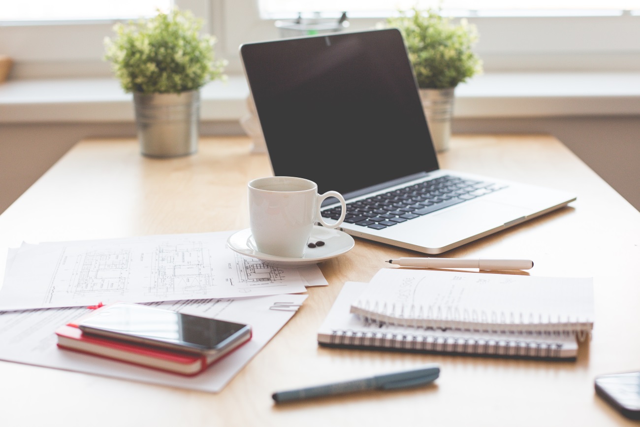 desk with laptop, coffee mug, and paperwork