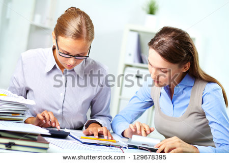 stock-photo-portrait-of-two-young-businesswomen-working-with-calculators-in-office-129678395